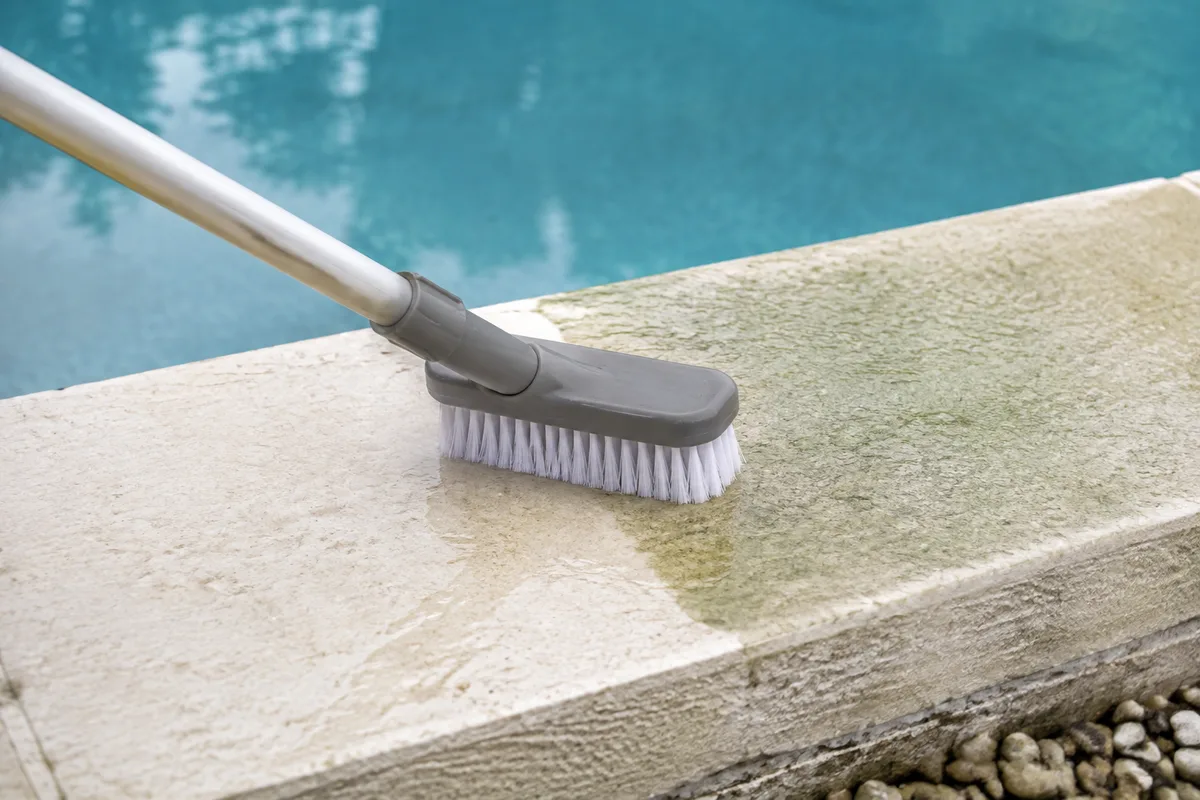 Nettoyage à la brosse d&rsquo;une margelle de piscine en pierre claire